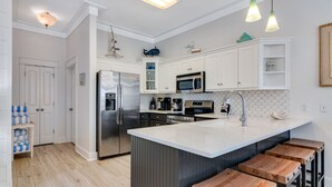 A modern kitchen with white cabinets, stainless steel appliances, and a central island with bar stools.