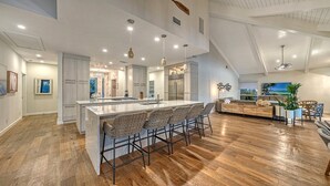 Una cocina amplia con una isla grande, electrodomésticos modernos y una zona de estar acogedora con vistas al exterior.
