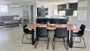 A modern kitchen with a central island, black chairs, and a wooden dining table.