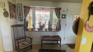 A room with a window, a chair, a bench, and a door.