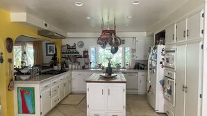 A spacious kitchen with white cabinets, a central island, and a large window providing natural light.
