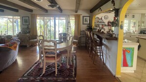 A spacious living area with a round table, multiple chairs, a sofa, and a kitchen area with a bar.