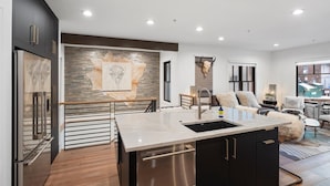 A modern kitchen with a central island, stainless steel appliances, and a stone backsplash. - The Silver Buffalo Suite in Downtown Whitefish (Whitefish)