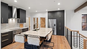 A modern kitchen with dark cabinetry, stainless steel appliances, and a marble island. - The Silver Buffalo Suite in Downtown Whitefish (Whitefish)