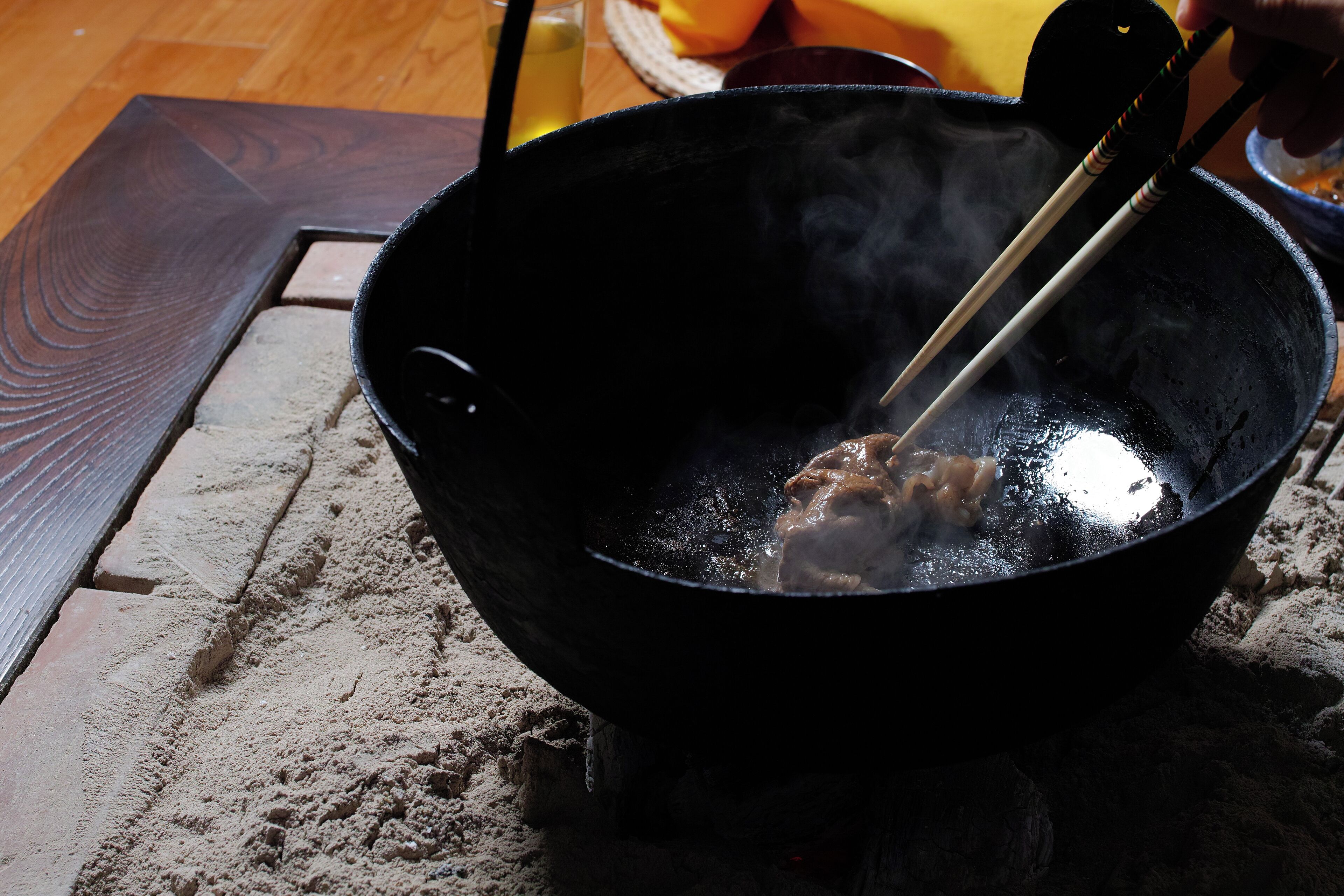 A wok on a stove with steam rising, indicating cooking.