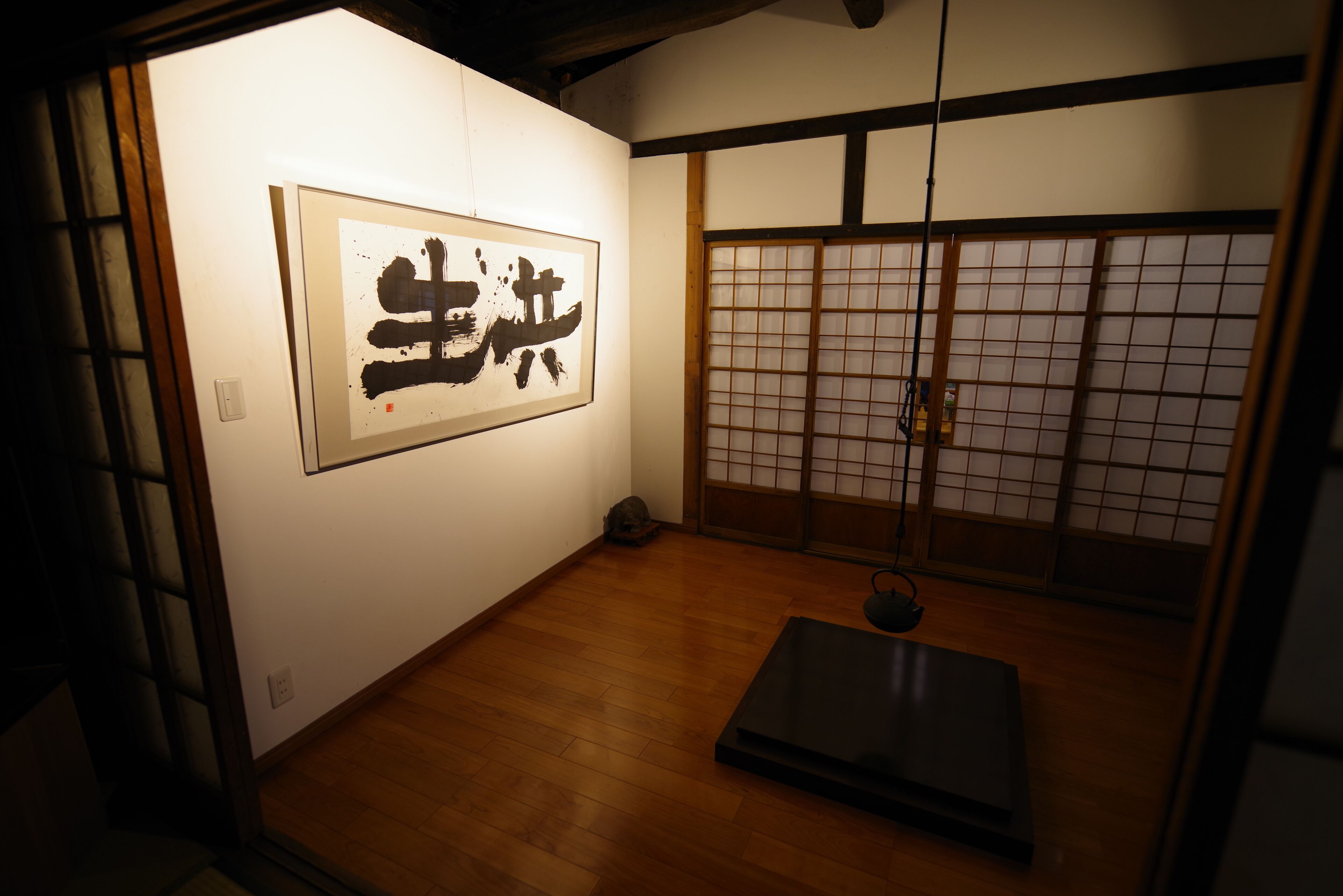 An art gallery with a framed calligraphy piece on the wall and a tatami mat in the center.