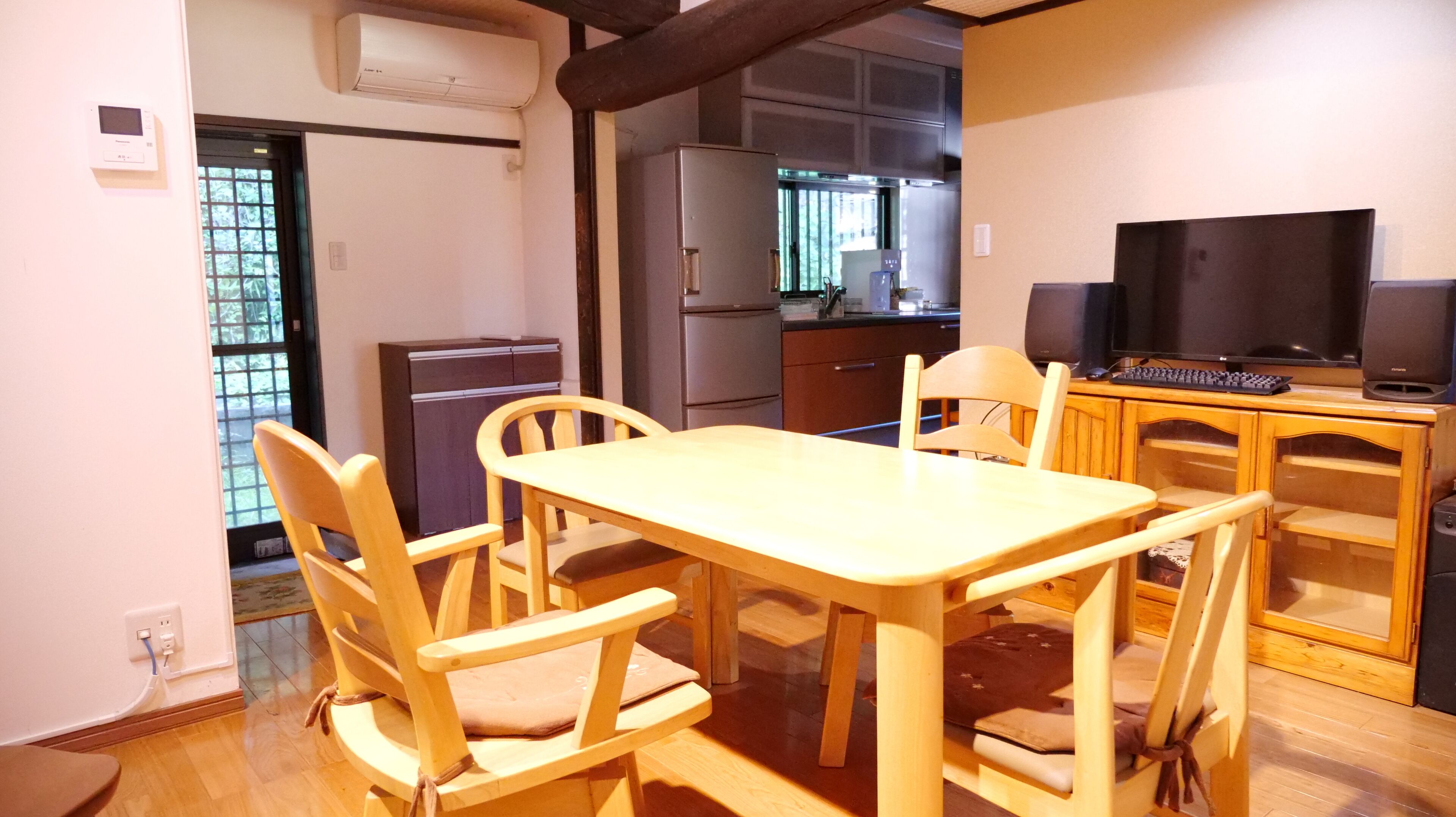 Una cocina compacta con comedor, que incluye una mesa, sillas, un refrigerador, una estufa y un televisor.