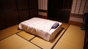 Una stanza con tatami, un letto, porte scorrevoli in legno ed un'estetica tradizionale giapponese.