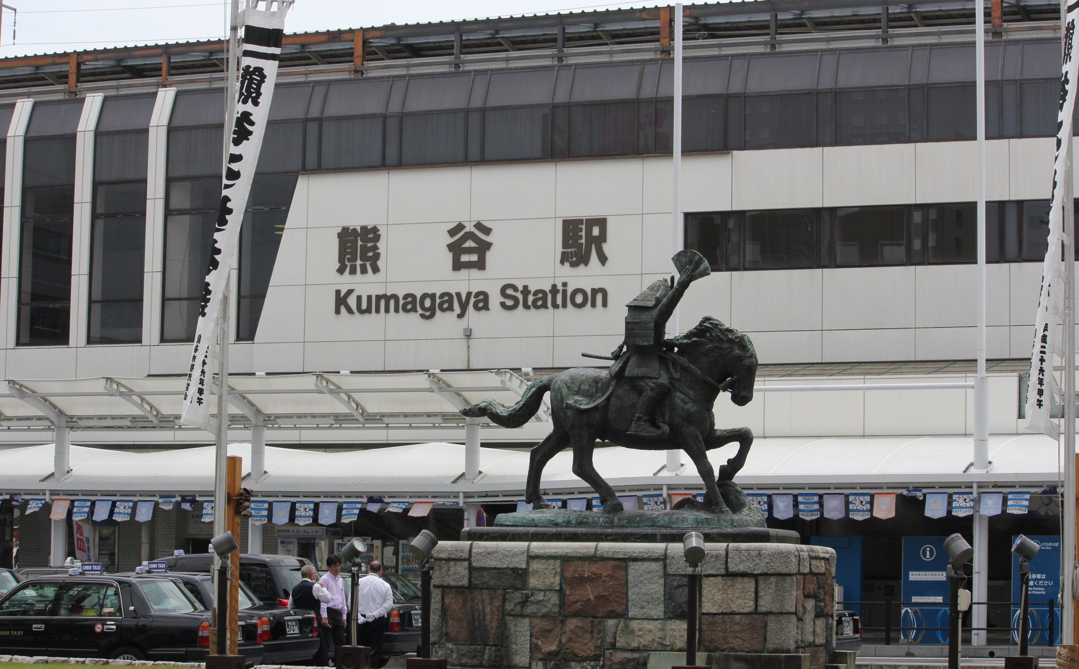 A statue of a man on a horse in front of Kumagaya Station.