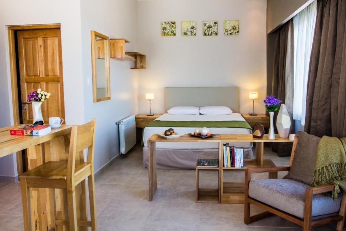 A bedroom with a bed, bedside tables, a desk, and a chair.