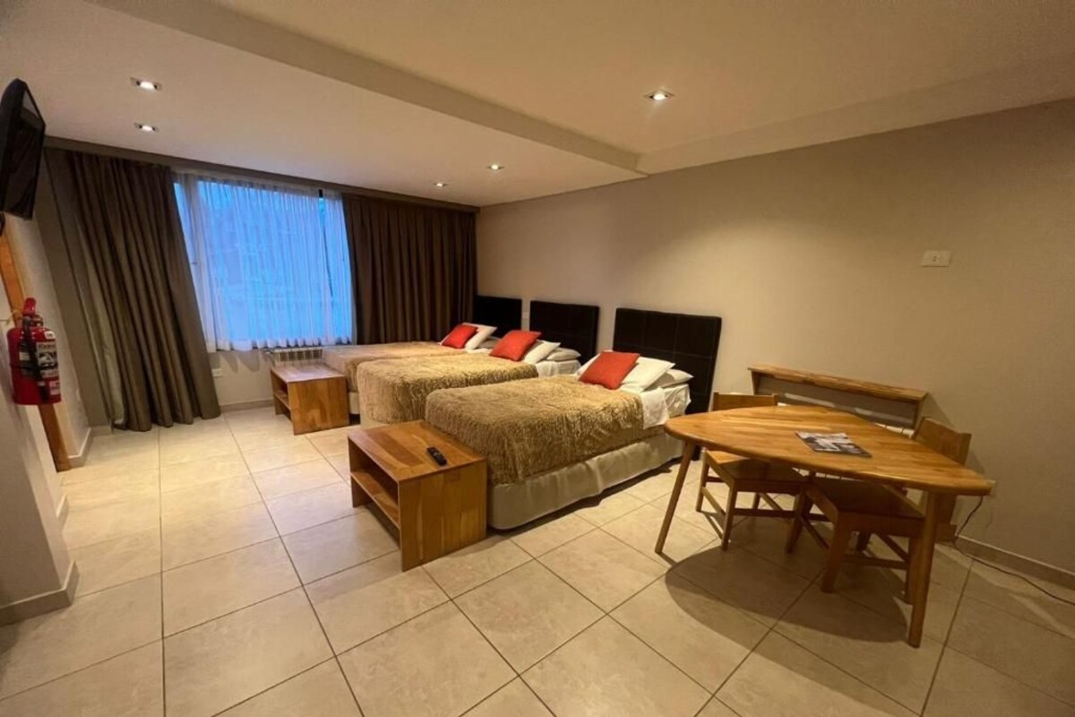 A hotel room with two beds, a wooden table, and a TV.