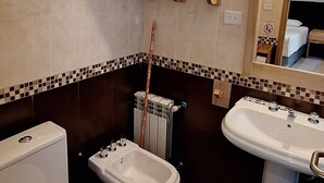 A bathroom with two toilets, a bidet, a sink, and a towel rack. - MIRALEJOS APART HOTEL (Ushuaia)