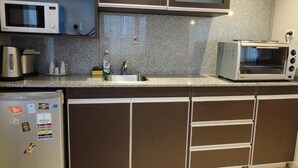 A kitchen with a microwave, toaster, and refrigerator. - MIRALEJOS APART HOTEL (Ushuaia)