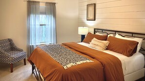 Une chambre à coucher comprenant un lit, une chaise, une table de chevet avec une lampe et un ventilateur de plafond.