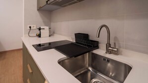 A modern kitchen with a stainless steel sink, a black drying rack, and a coffee machine.