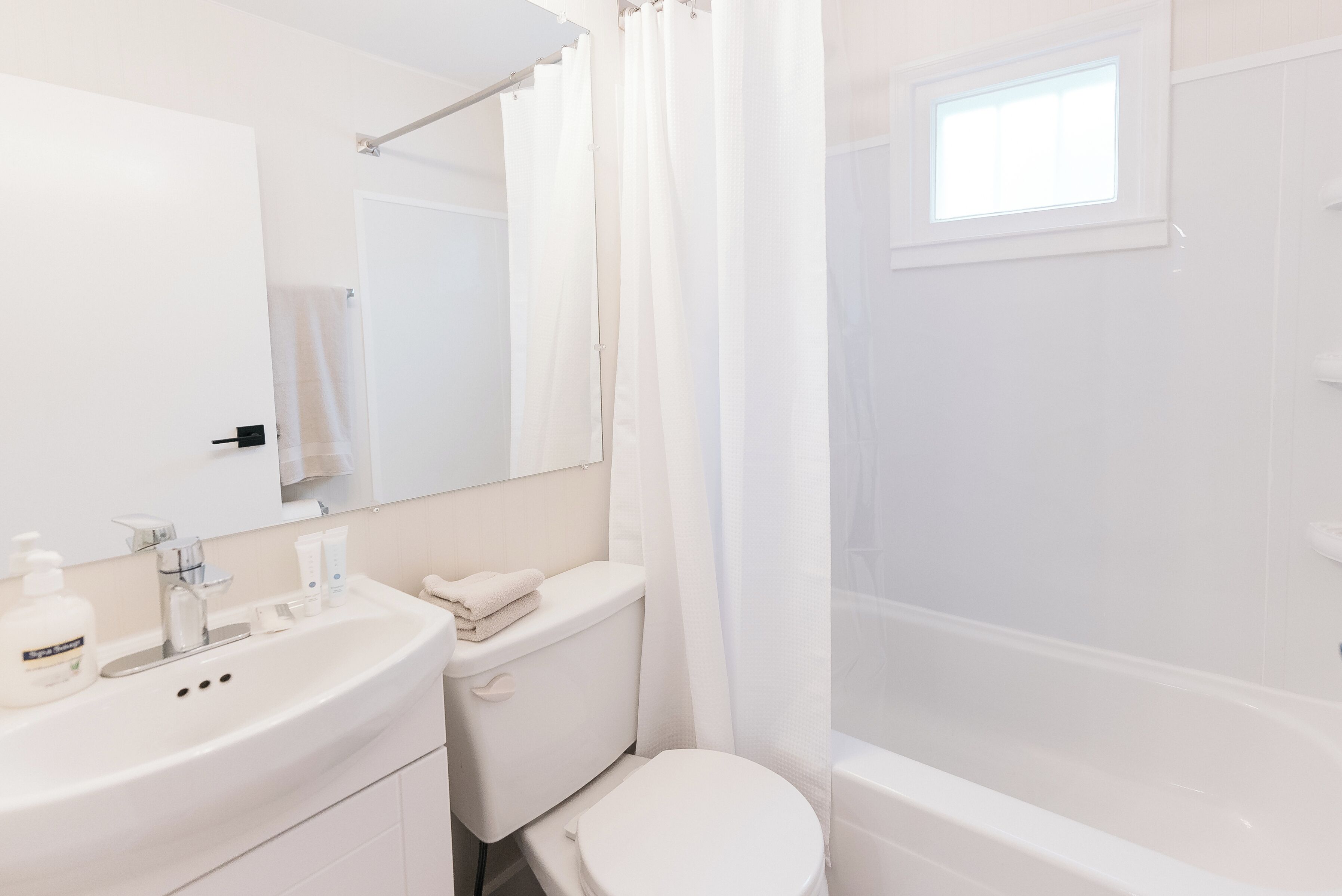 Ein modernes Badezimmer mit Waschbecken, Toilette und Badewanne, alles in Weiß.