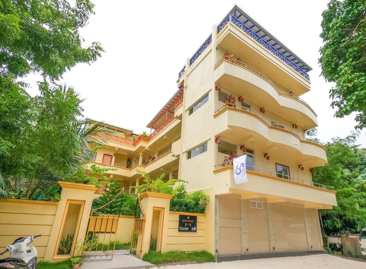 Un edificio de varios pisos con balcones, una entrada protegida por una reja y un cartel que indica que es un hotel.