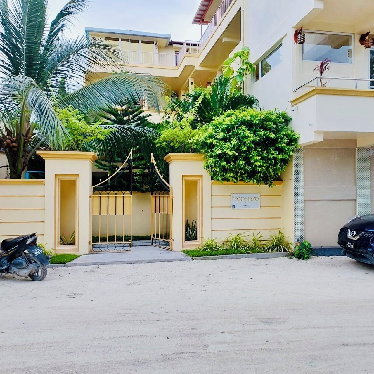 Ein Wohngebäude mit befahrbarer Durchfahrt, einem Schild mit der Aufschrift "Soren 170" und einem abgestellten Motorrad.