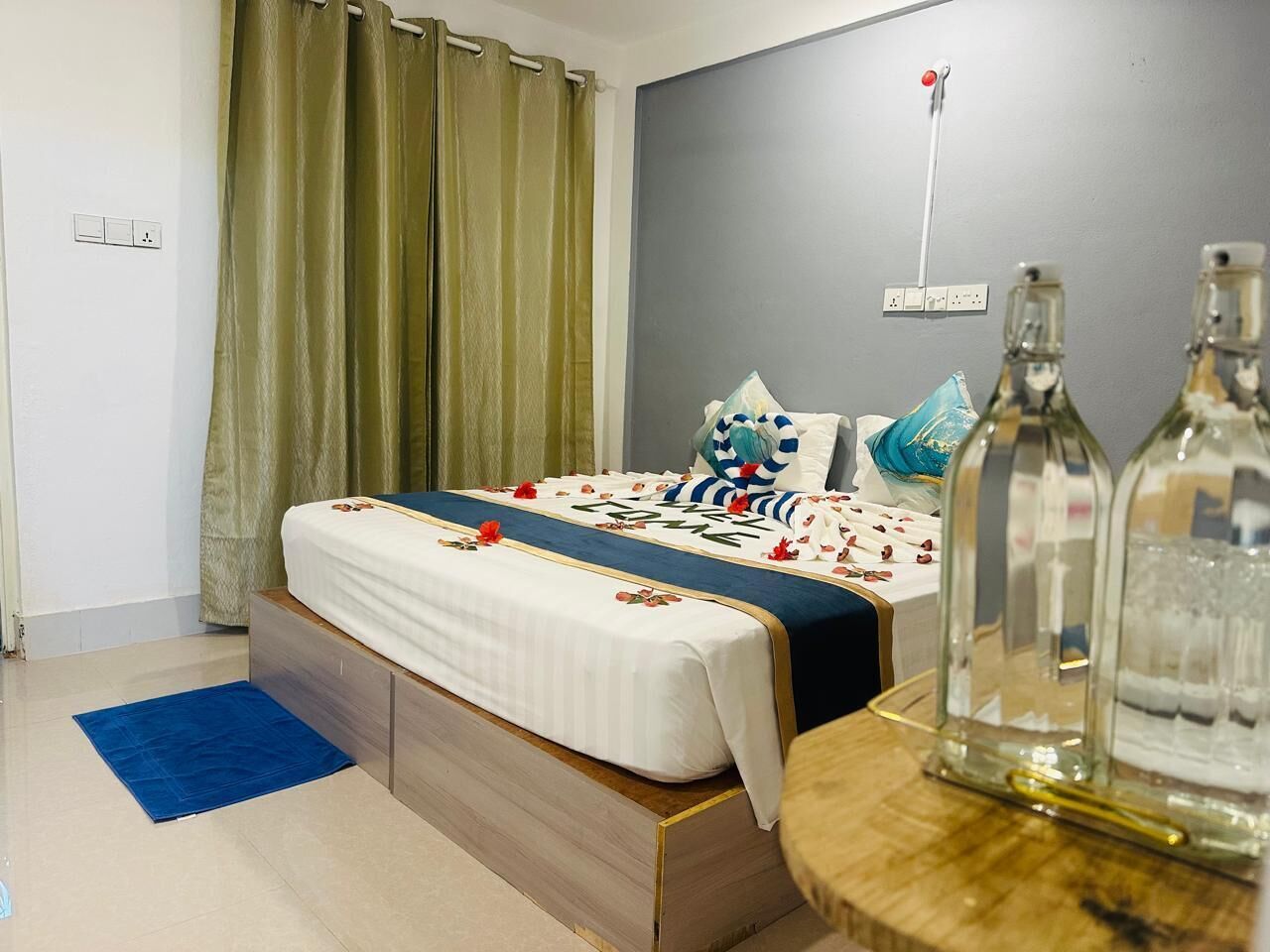 A bedroom with a bed, a nightstand, a lamp, and a window with curtains.