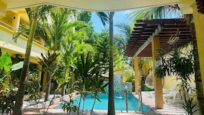 A pool area with a clear view of the pool, surrounded by palm trees and a covered seating area. - SORENZO Maldives  (Thoddoo)
