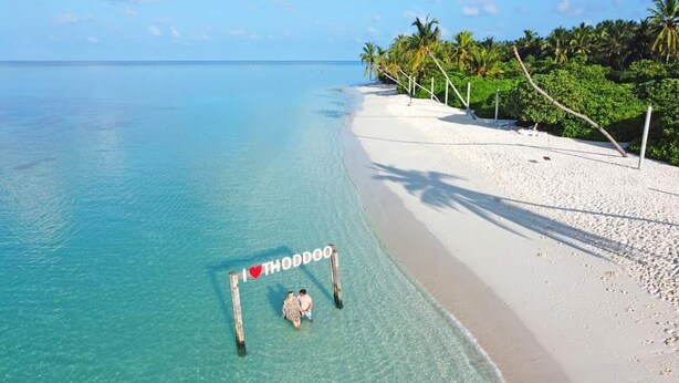 A beach with clear turquoise water, white sand, and palm trees. - SORENZO Maldives  (Thoddoo)