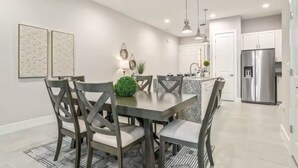 A modern kitchen with a central island, stainless steel appliances, and a dining area with a dark wooden table and chairs. - Amazing home in Orlando just 5 minute away from Disney World (Kissimmee)