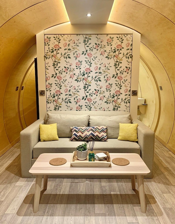 Une pièce chaleureuse avec un canapé, une table basse en bois et un papier peint à motifs floraux.