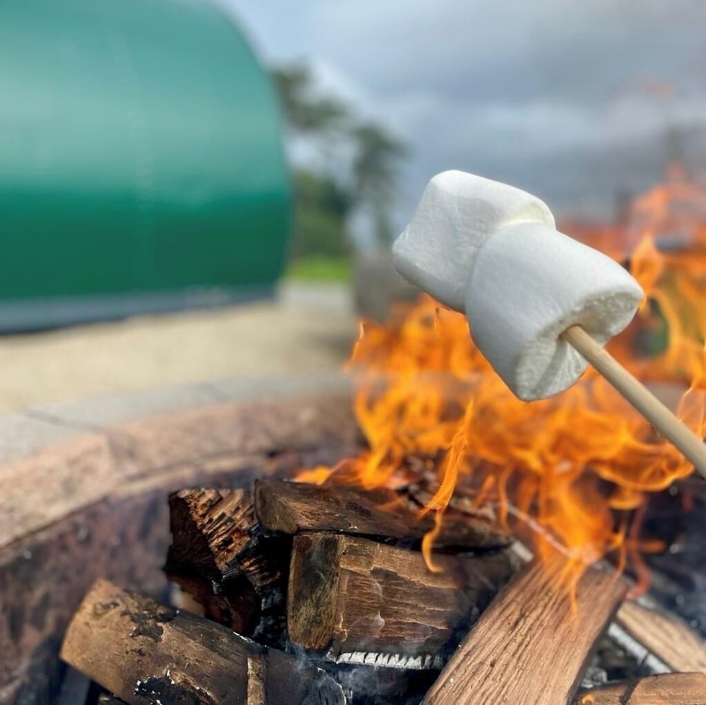 A marshmallow on a stick over a campfire.