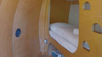 A compact, curved room with a bunk bed and a small storage area.