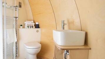 A compact bathroom with a white toilet, a sink, and a shower area.