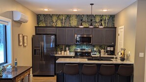 Una cocina moderna con armarios oscuros, un refrigerador de acero inoxidable, un microondas y una isla grande con taburetes de bar.