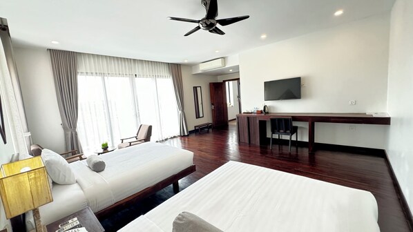 A hotel room with a large bed, a desk, a television, and a ceiling fan. - Mealy Villa (Siem Reap)