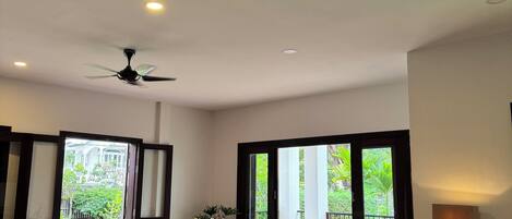A spacious living room with a red sofa, a coffee table, and a ceiling fan.