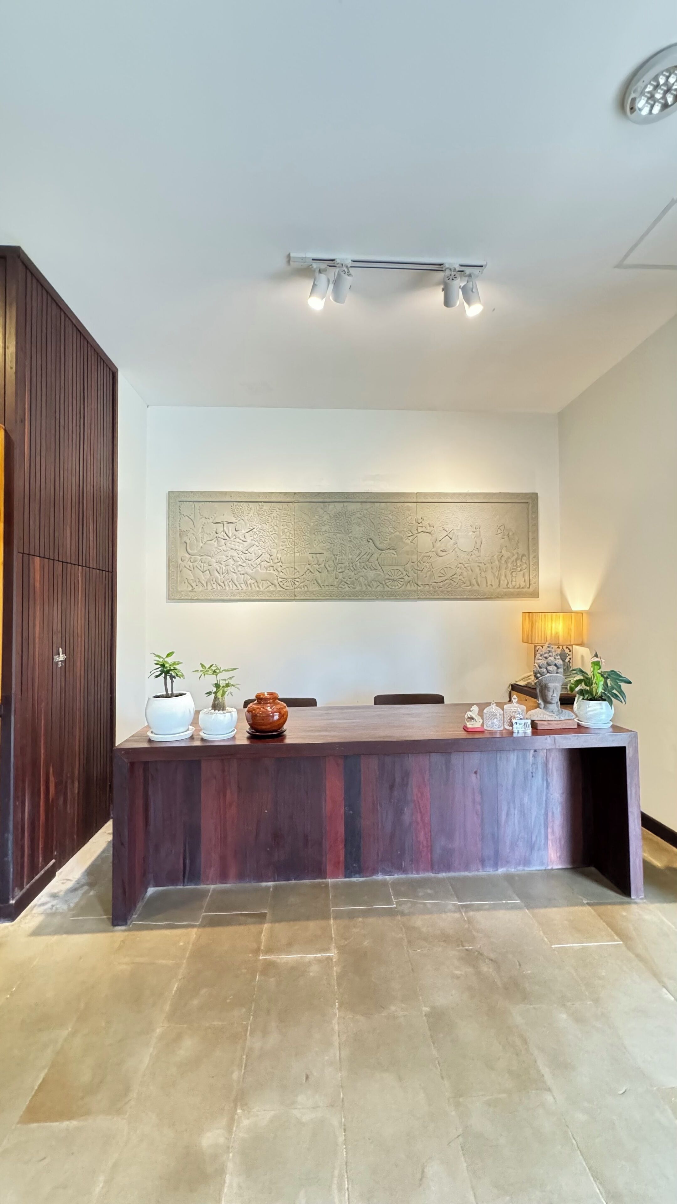 A reception desk with a wooden finish, a large abstract artwork above it, and a floor with a patterned tile design.