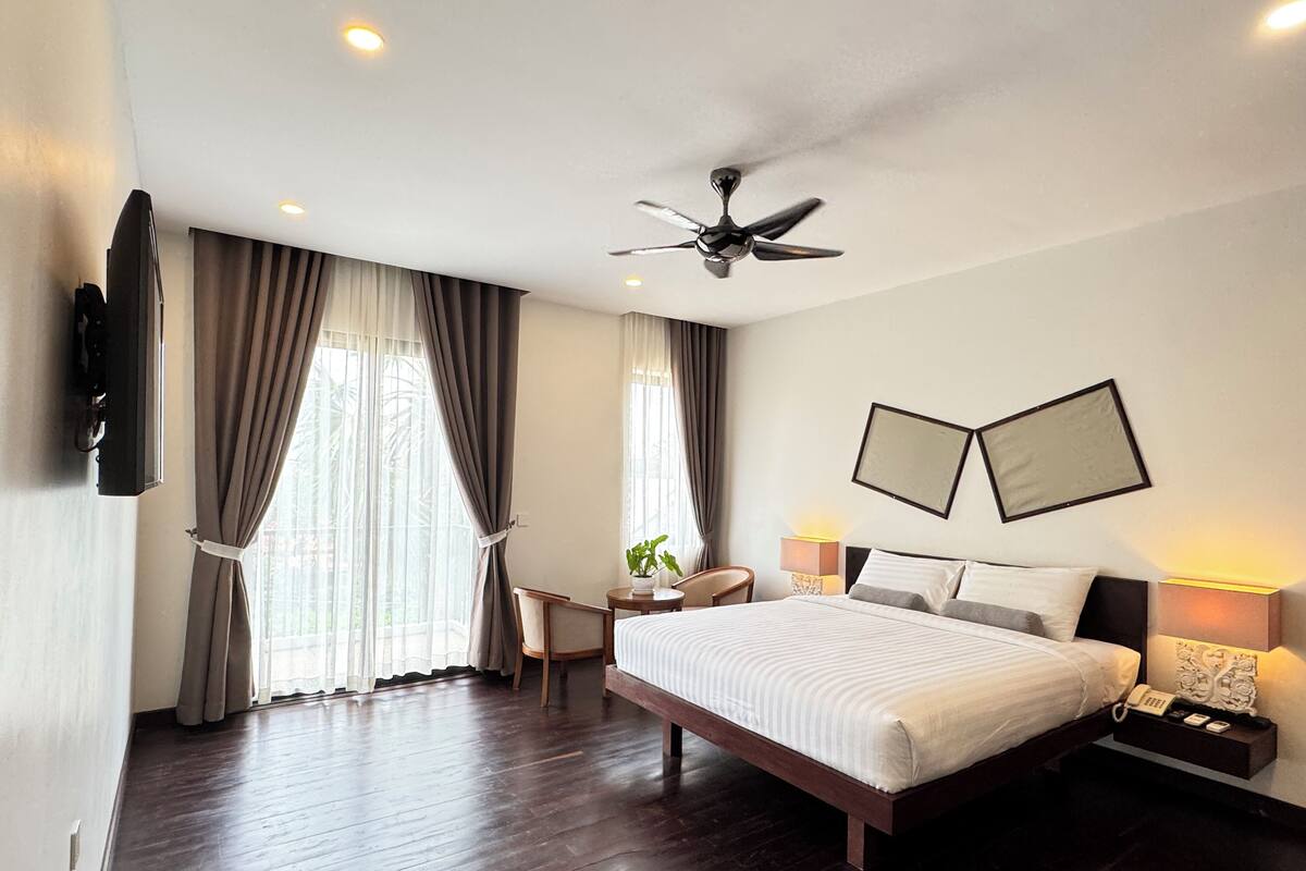 Una habitación de hotel moderna con una cama grande, ventilador de techo y dos mesitas de noche con lámparas.