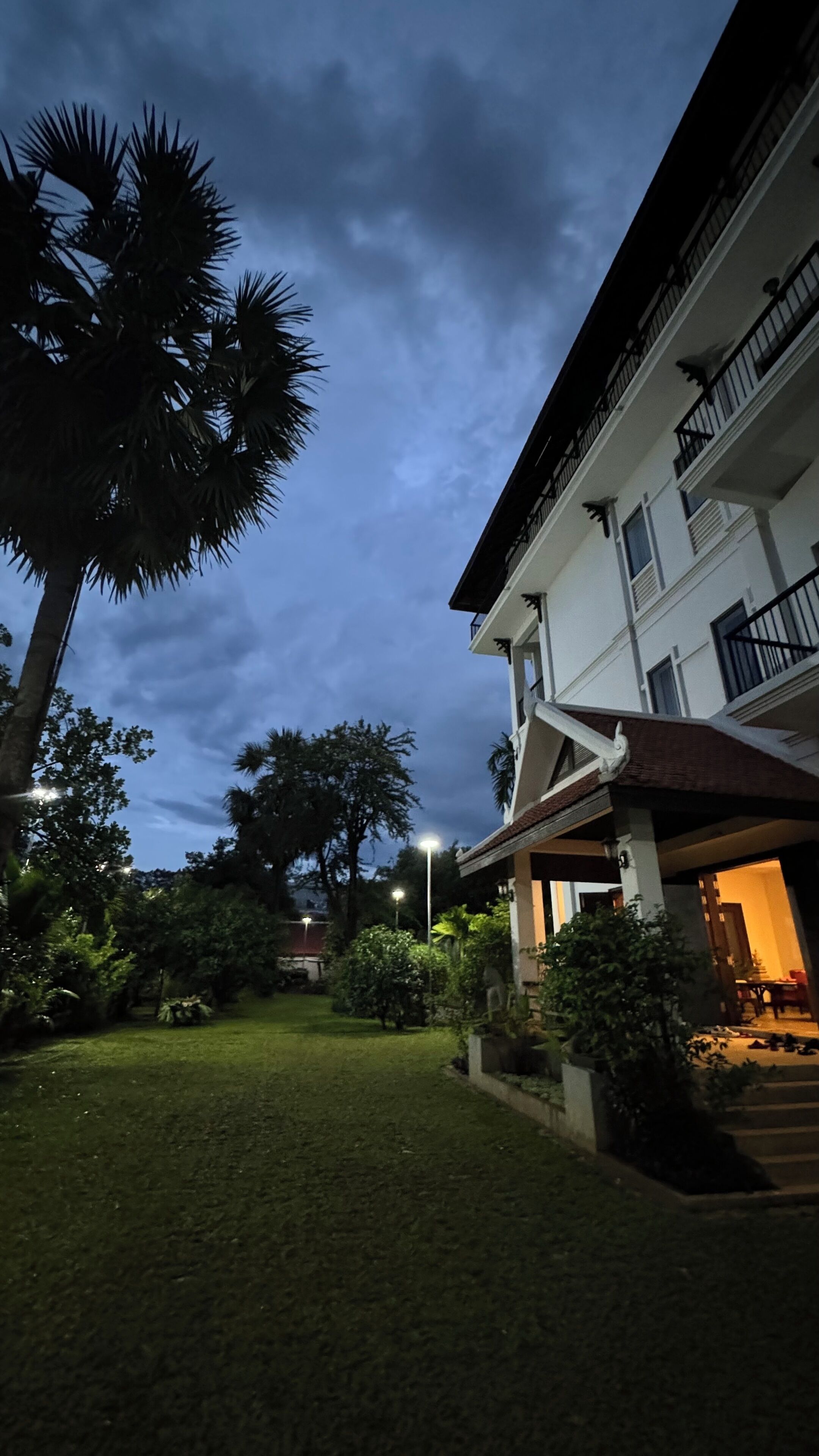A residential building with a balcony and a well-maintained lawn.