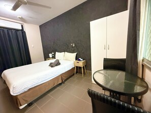 A hotel room with a bed, a nightstand, a table, and a wardrobe. - Tropical River Hotel (Katherine)