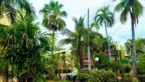 A hotel with multiple floors, surrounded by lush greenery and palm trees. - Tropical River Hotel (Katherine)