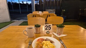 A table with a plate of food, a coffee cup, and numbered chairs. - Tropical River Hotel (Katherine)