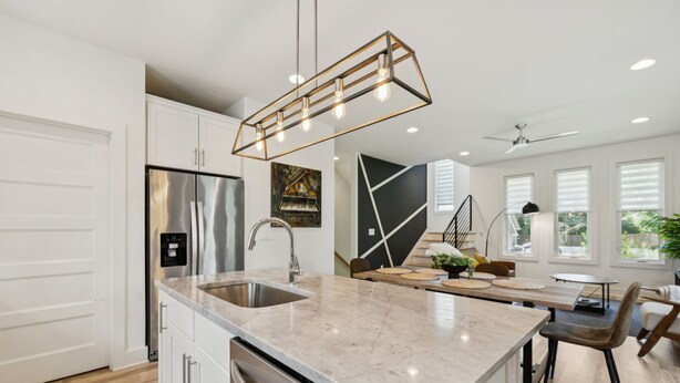 A modern kitchen with a stainless steel refrigerator, a built-in dishwasher, and a marble countertop. - Modern House minutes from Broadway (Nashville)