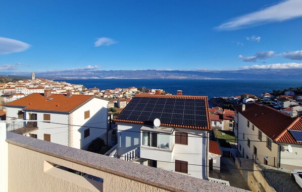 A coastal town with buildings featuring red-tiled roofs and a prominent church tower.