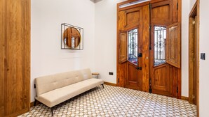 Una stanza con un armadio in legno, un divano beige, un piccolo tavolino rotondo e un pavimento decorato.
