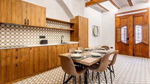 Una cucina moderna con mobili in legno, zoccolo rivestito in piastrelle e zona pranzo con tavolo e sedie di legno.