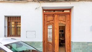 Un edificio bianco con una porta e una finestra in legno, dotate di inferriate metalliche.
