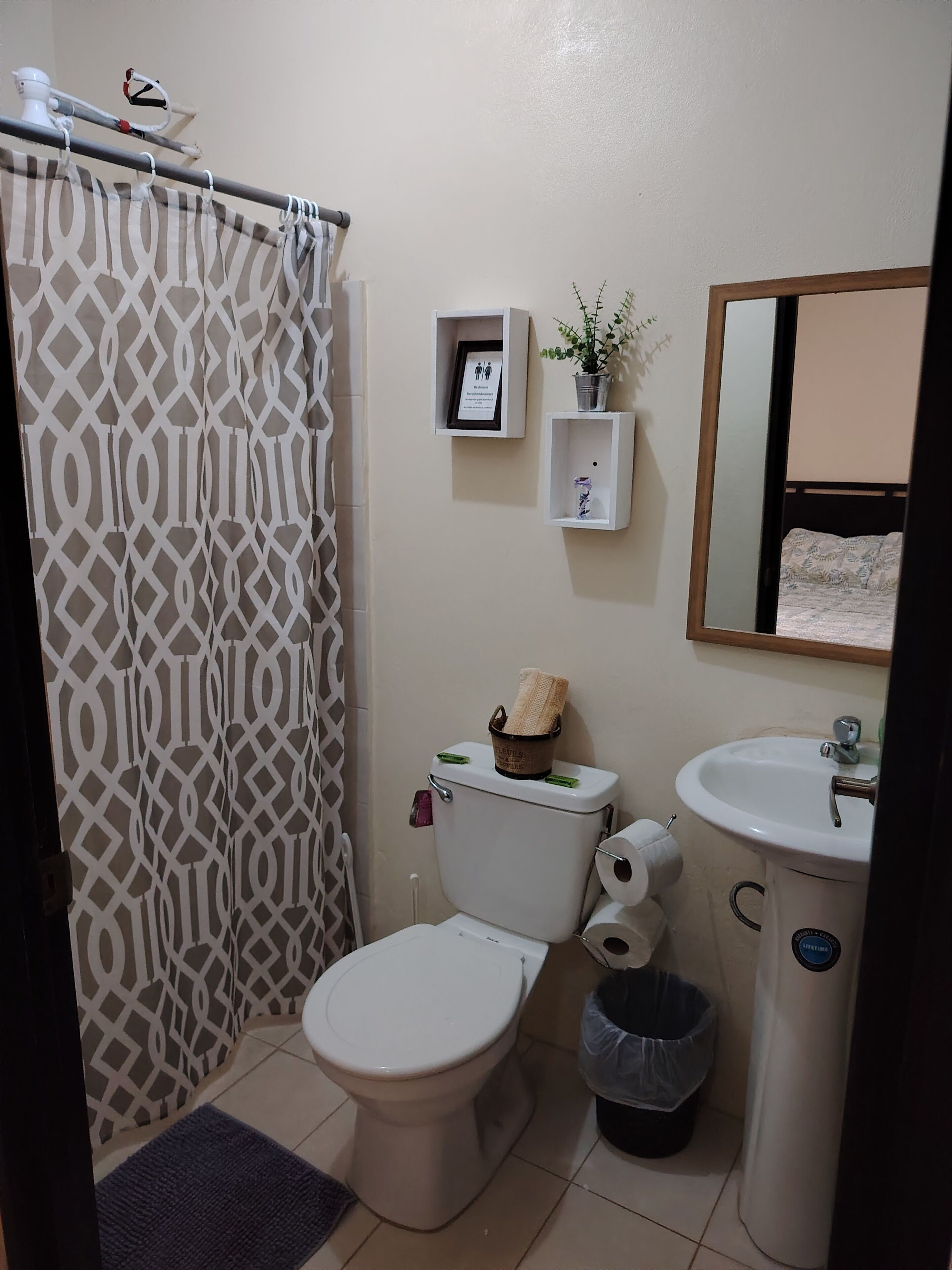 A bathroom with a toilet, bidet, sink, and a shower curtain.