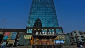 A tall, modern hotel with a glass facade, signage for the World Trade Center S'aw Boutique Hotel, and a digital display at the entrance.