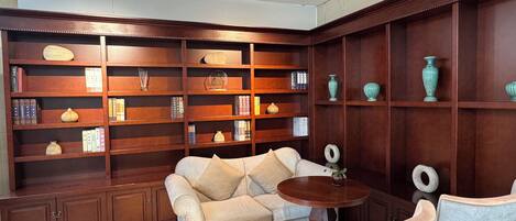 A room with a sofa, a round table, and wooden shelving with decorative items.
