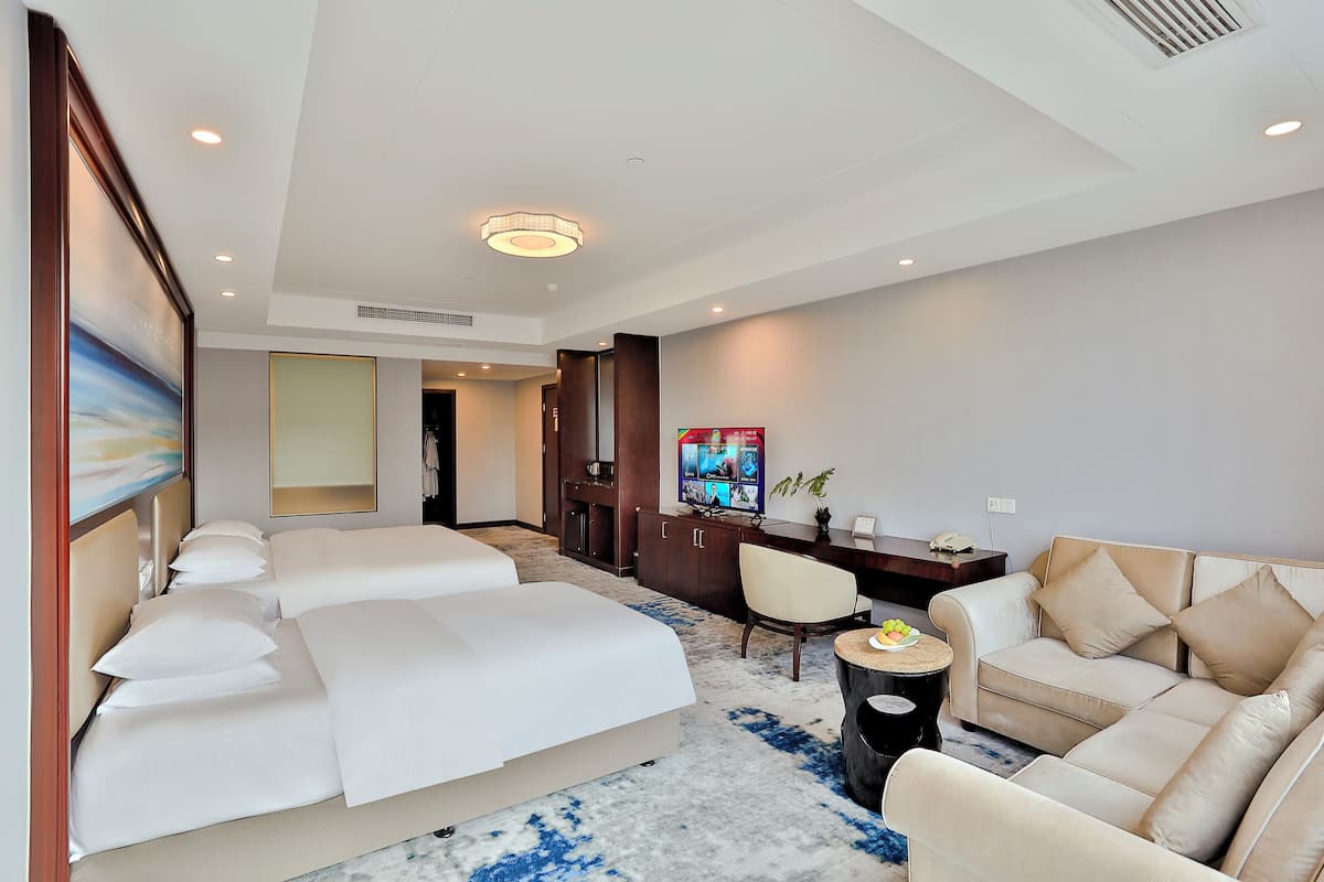 A hotel room with a large bed, a sofa, a TV, and a desk with a chair.