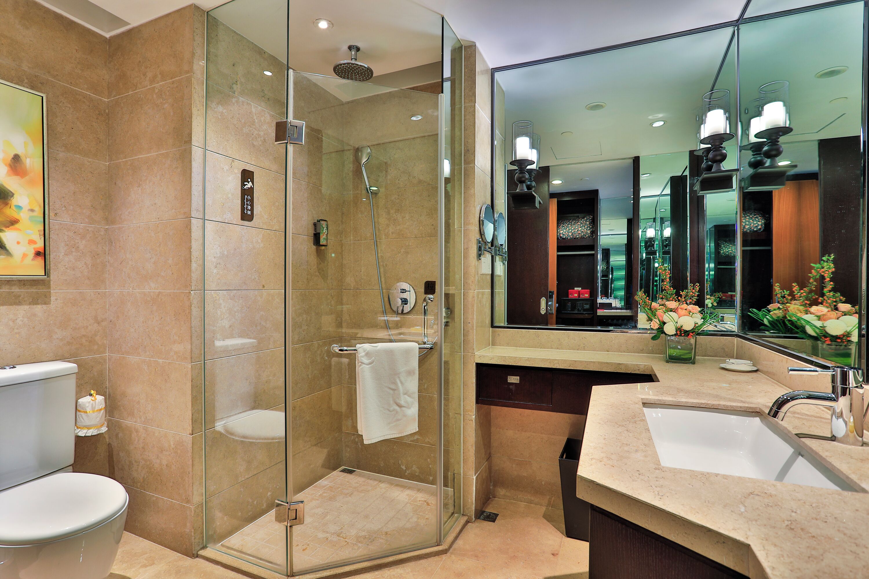 A modern bathroom with a glass-enclosed shower, a toilet, a sink, and a large mirror.