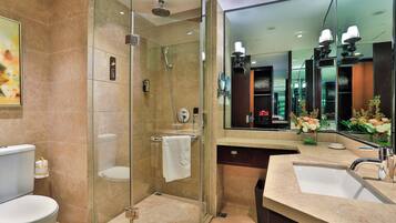 A modern bathroom with a glass-enclosed shower, a toilet, a sink, and a large mirror.